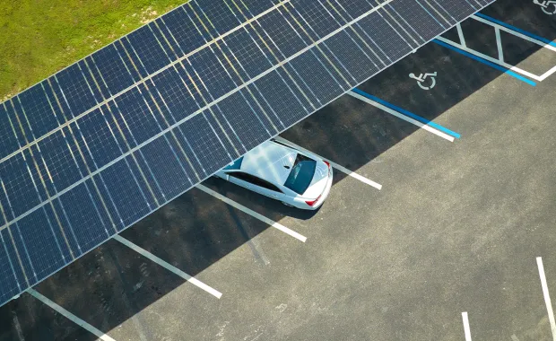 a car parked underneath a solar panel roof in a public lot