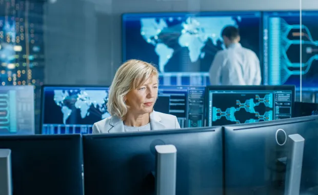 female cybersecurity analyst monitoring multiple screens in a security operations center