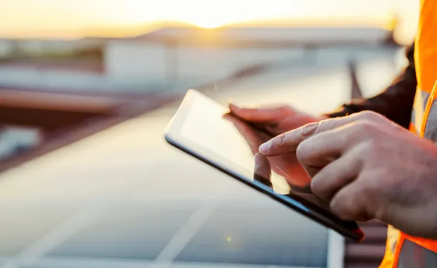 person holding a tablet in front of a solar farm