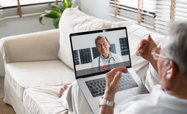 Äldre man som samtalar med sin läkare digital på en laptop
