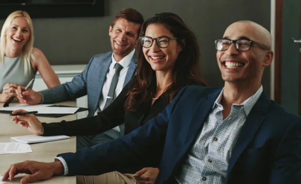 Four business people smiling while listening to a speaker