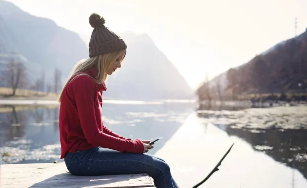 Girl sitting by the water on phone
