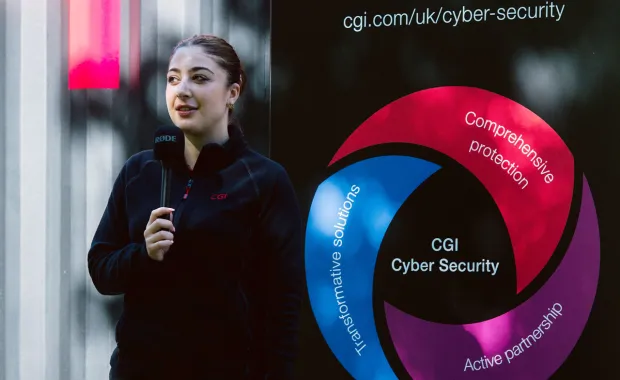Graduate doing interview in front of CGI Cyber Escape escape room