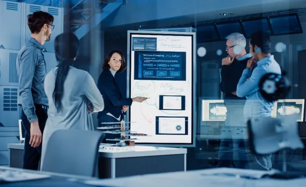 Group of engineers collaborating around a digital board