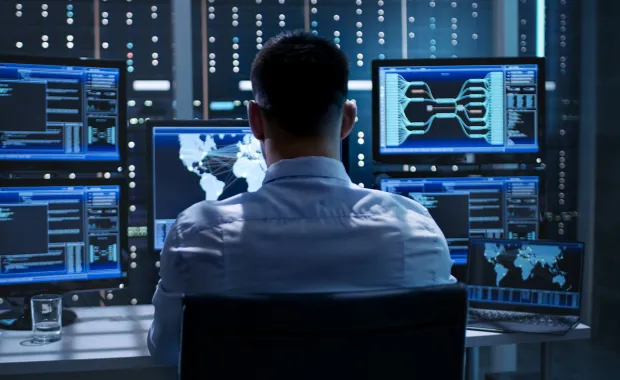 Cyber security professional looking at computer screens 
