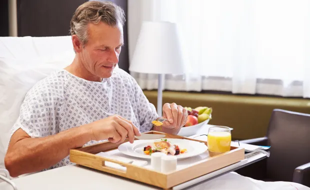 Manlig-patient-intar-måltid-i-sjukhussäng