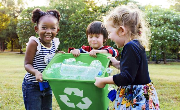 3 small children carrying a recycling bin