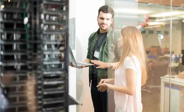 Man and lady conversing in Server room with laptop open