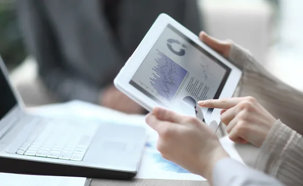 une tablette affichant des données, avec un ordinateur portable en arrière-plan