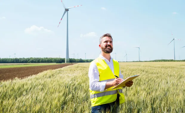 Utilities field worker check wind turbine in a field with a hand held device
