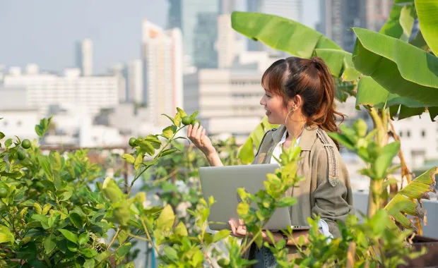 Woman happing looks at the plants holding a laptop
