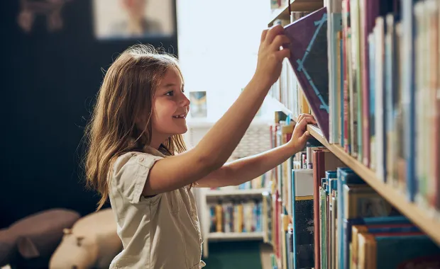 CHild removes a book from a library shelf