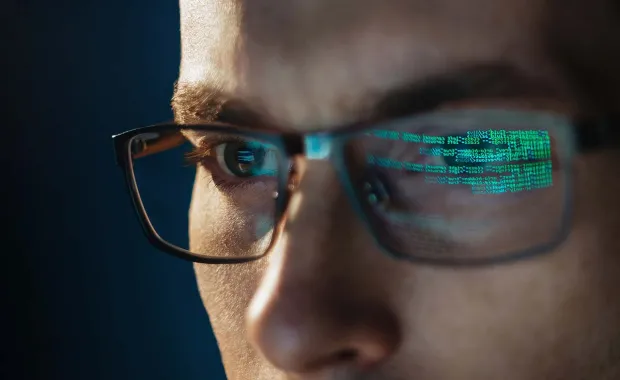 Un homme avec des lunettes regarde un ordinateur
