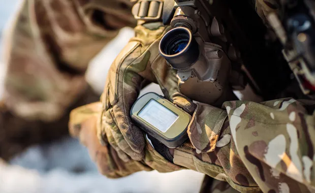 Soldat som tittar på en digital karta som sitter på ena armen