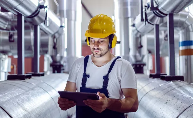 Travailleur masculin portant un casque regardant une tablette dans une usine de fabrication