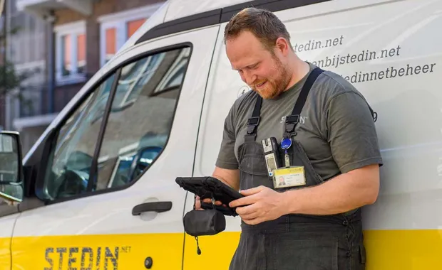 Mobile network engineer looking at a tablet in front of his van