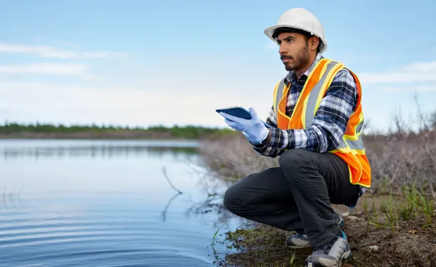 Worker using tablet device by a river bank