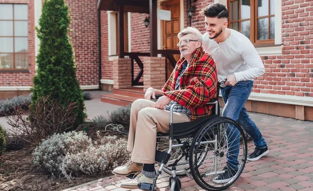 Un jeune poussant une personne âgée dans un fauteuil roulant