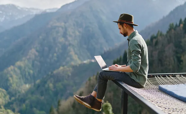 digital nomad using laptop in mountains