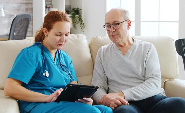 Patient âgé en visioconférence avec un médecin depuis son domicile à l’aide d’un ordinateur portable