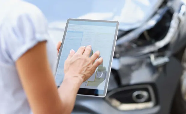 insurance consultant standing by car uses tablet device