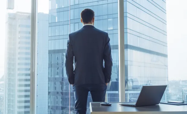 IT consultant in suit faces away from camera looking out office window