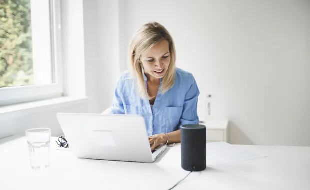 consultant working on a laptop next to a smart speaker