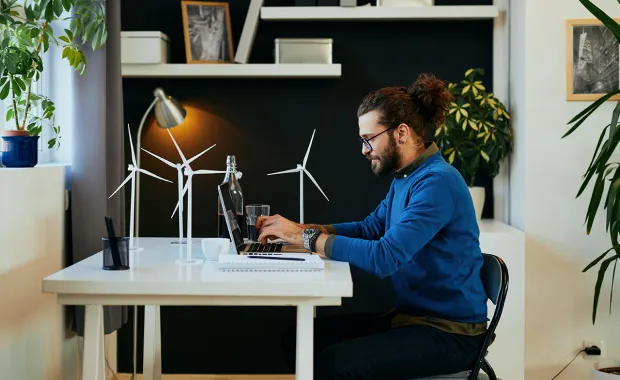 man working from home at desk with small model wind turbines