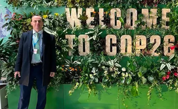 Michael Herron standing by Welcome to COP26 sign