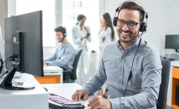 service support help desk consultant wearing headset sat at desk