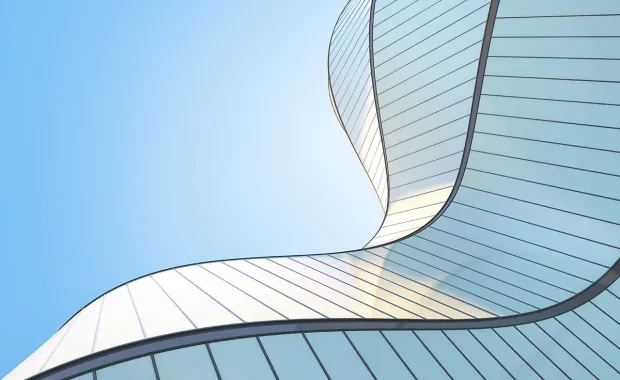 Upwards angle view of an abstract silver wave shape building and blue sky