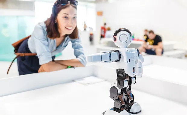 Lady smiling whilst examining robot
