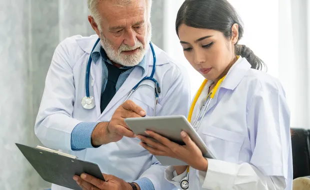 Doctor using tablet computer while discussing with another doctor at the hospital