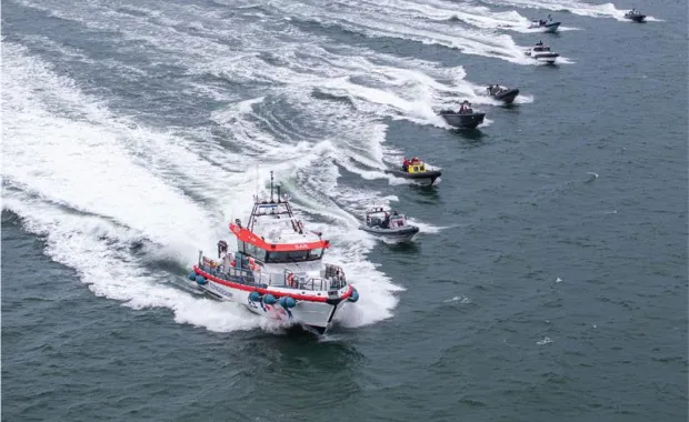 a line of boats driving across water