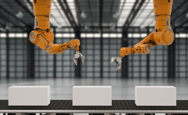Gula robotarmar rör sig över vita paket på paketband i industrilokal