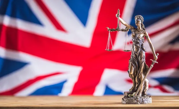 Lady Justice statue in front of Union Jack flag