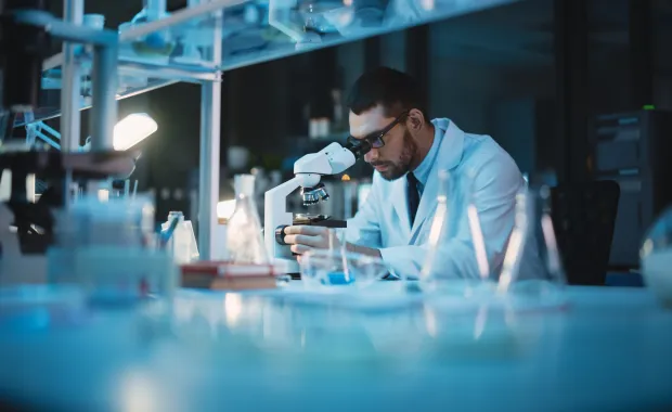 Life sciences researcher working at a microscope in a laboratory