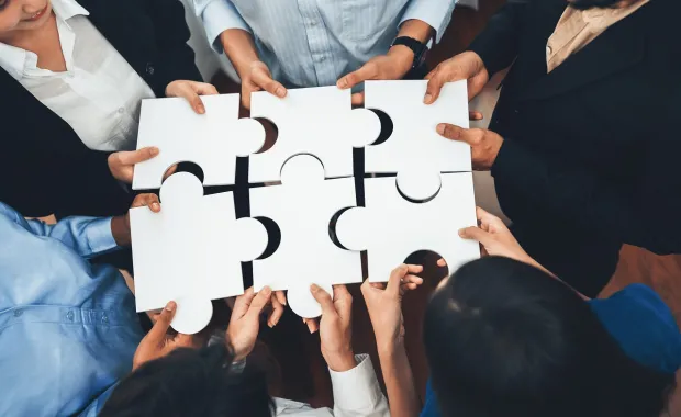 Group of people holding large puzzle pieces together