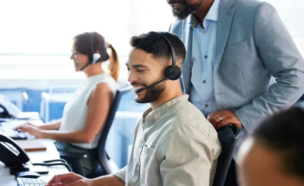 Smiling man in call centre at desk wearing headset