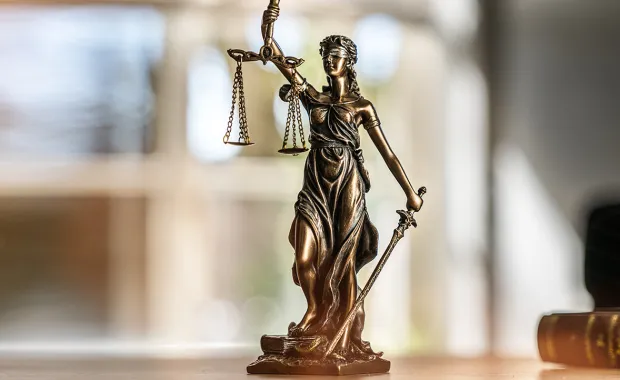 Small statue of Lady Justice on a wooden desk 