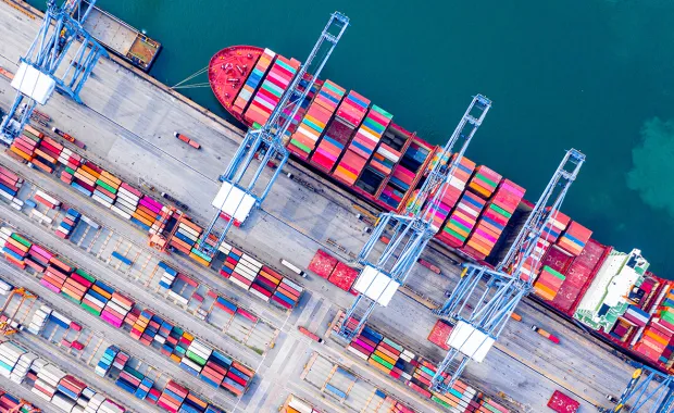 Arial view of a shipping yard with a docked cargo ship with containers lined in rows 