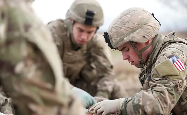 Military medical personnel treating a soldier in the field