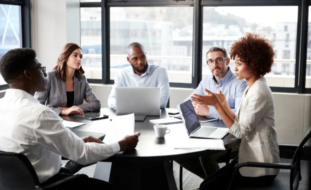 Millennial black business woman addressing colleagues at a corporate meeting