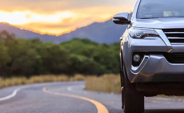 Stylish car on an open road surrounded by nature at sunset