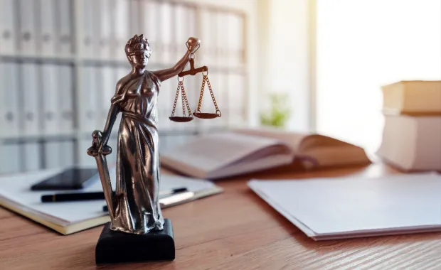 Bronze Lady Justice statue holding scales and a sword on an office desk