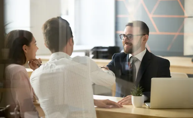 A couple and a consultant shaking hands across a desk