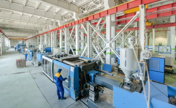 Töötaja opereerib suurt tööstusliku tootmismasinat