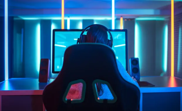 Ryggen av en kvinna i gaming stol framför en dator