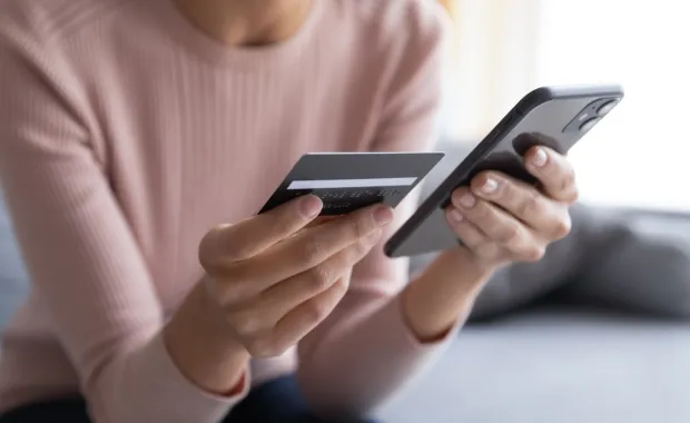 A person holding a credit card and a smartphone