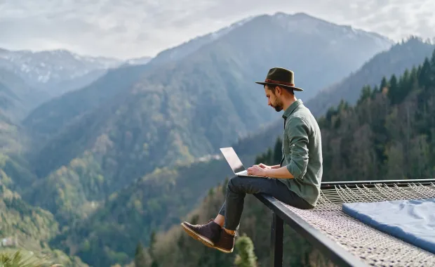 Person working on a laptop sitting on a mountain overlook